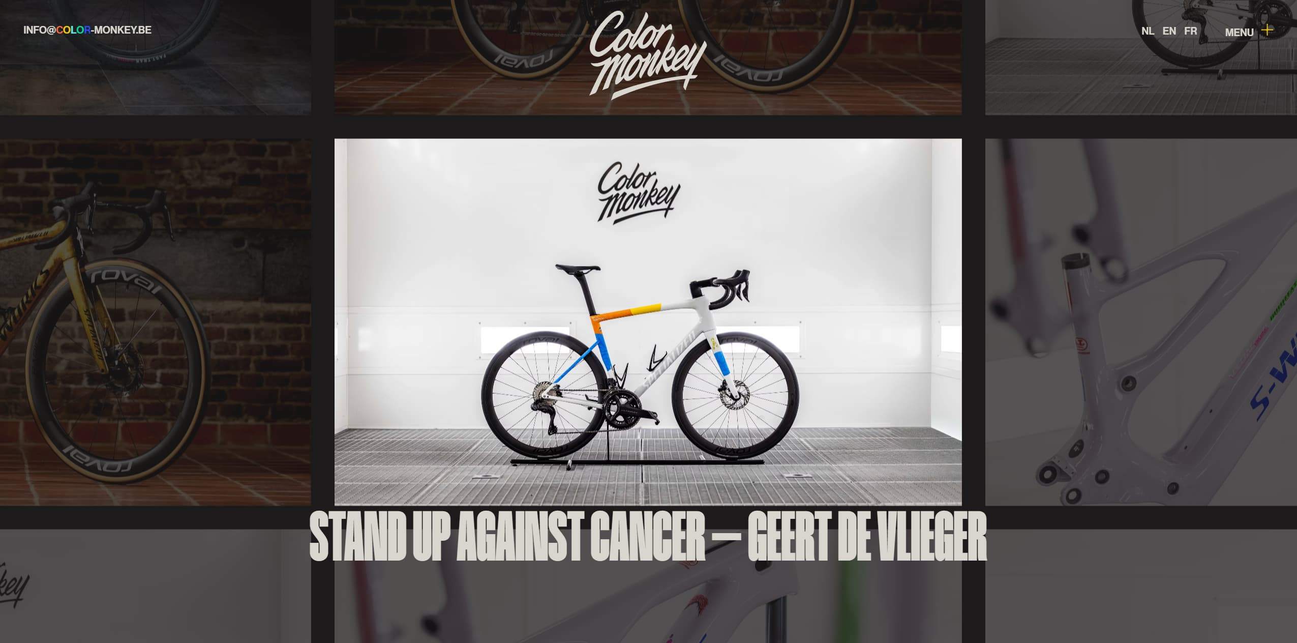 A white bicycle in a clean showroom with a Color Monkey logo on the wall above. The bike is centered with a sleek, modern frame and multicolor accents.